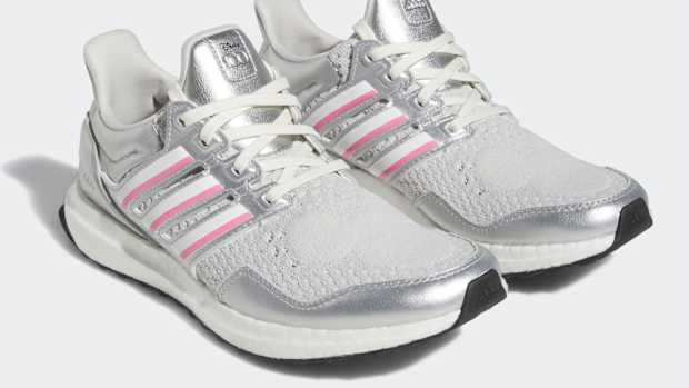 View of silver, white, and pink adidas shoes.